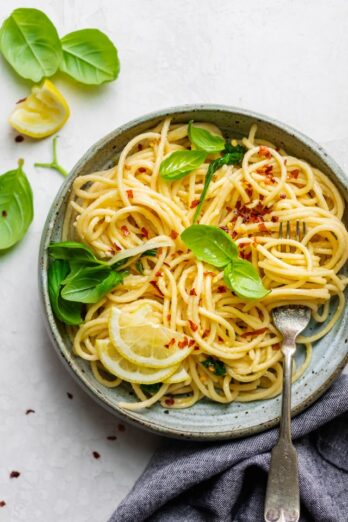 Final plated dish of the hummus pasta topped with lemon slices, basil and crushed garlic