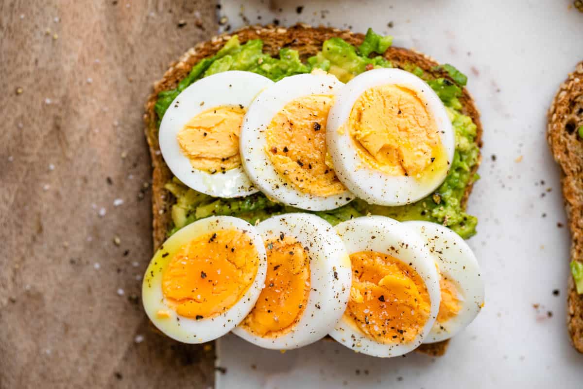 Toasted slice of bread with avocado mashed and slices of boiled eggs