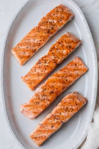 Grilled salmon on a white dish before topping with the citrus salsa