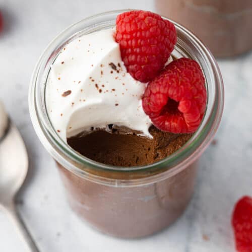 Three jars of avocado chocolate mousse with a small spoon on the side