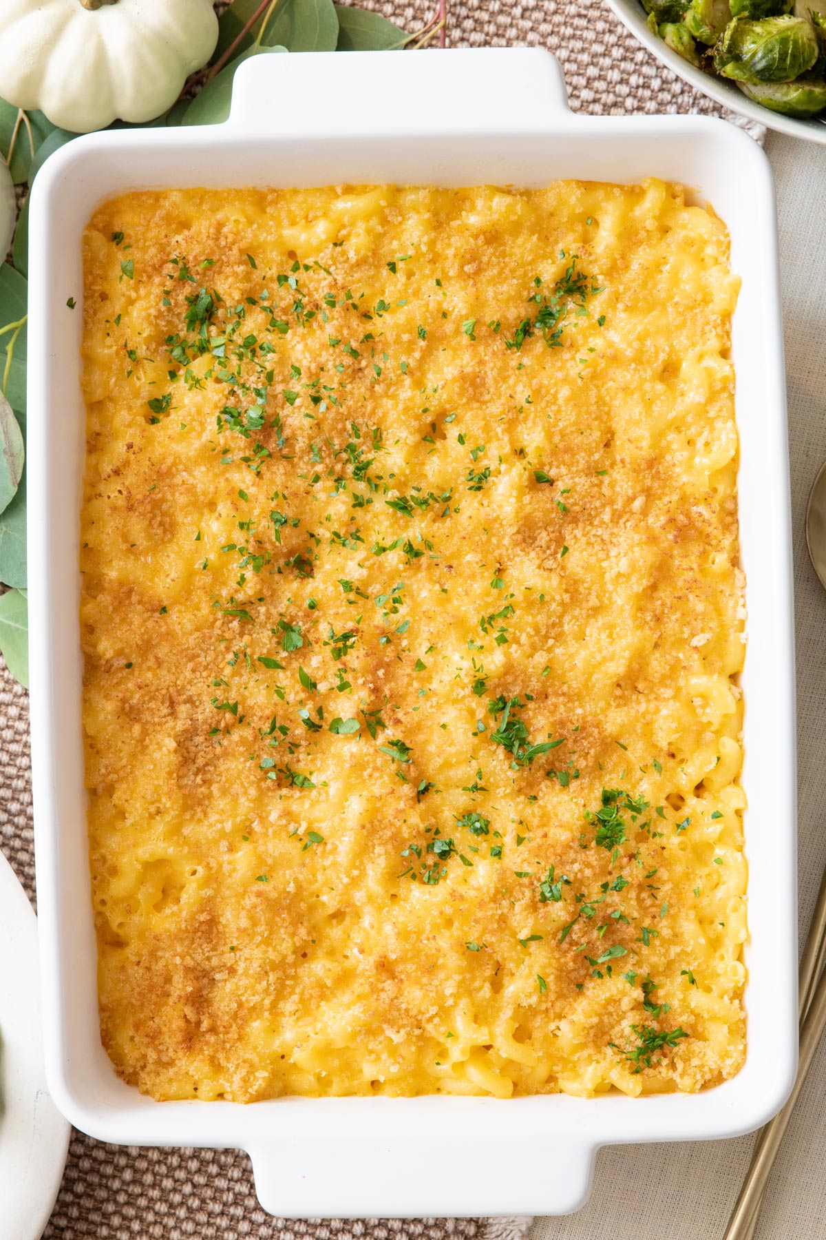 Baked macaroni and cheese in rectangle white baking dish garnished with fresh herbs.