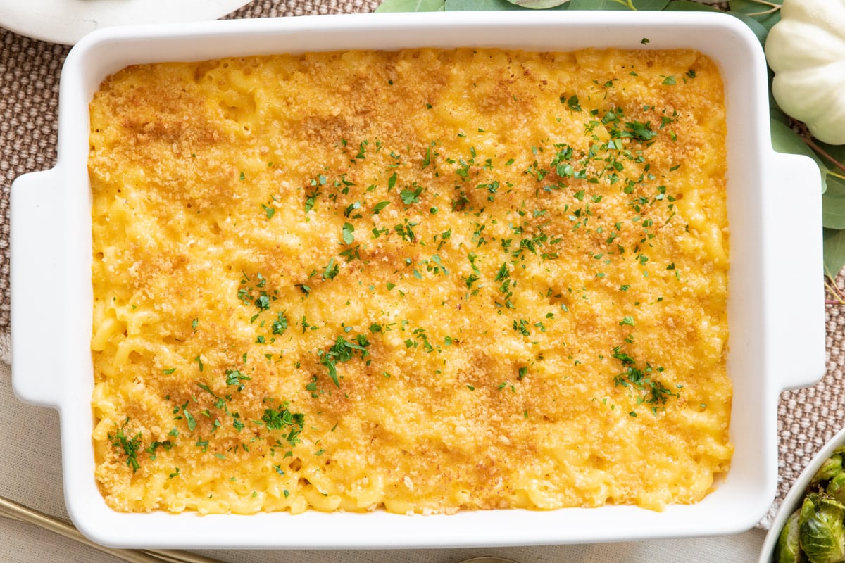Baked macaroni and cheese in baking dish garnished with fresh herbs.
