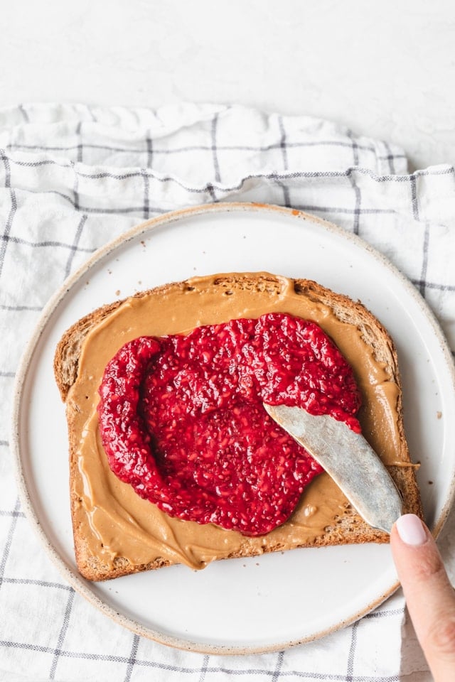 Spreading chia seed jam on toast with peanut butter