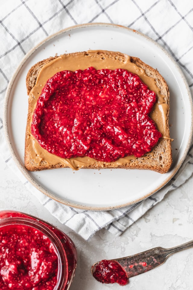 Chia seed jam on toast with peanut butter next to mason jar with more jam