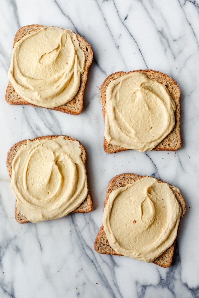 Four pieces of toast with hummus spread on all of them