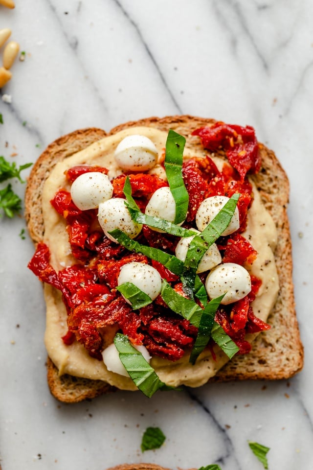 Hummus toast with sundried tomatoes, mozzarella and basil