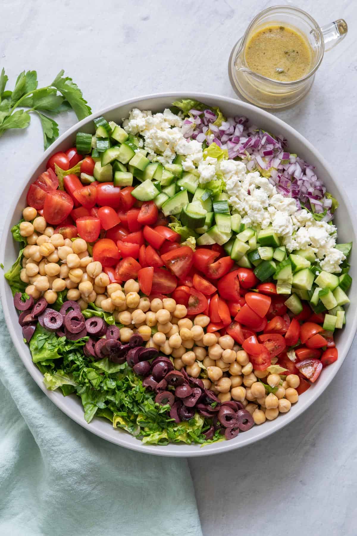 Overhead shot of chopped salad with ingredients layered in rows over lettuce.