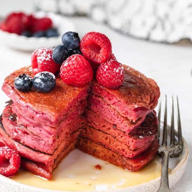 Stack of pink pancakes cut with fork on the side