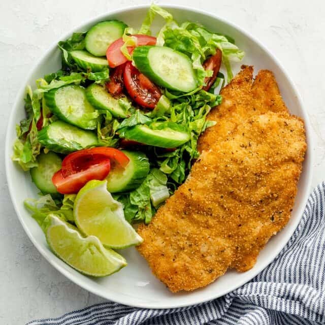 Plated breaded air fryer chicken breasts served with a side salad
