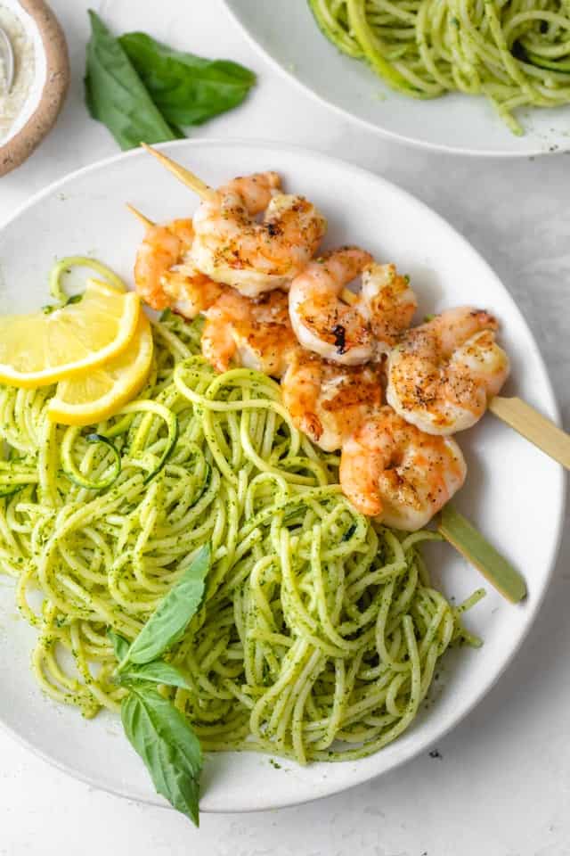Plate of pesto spaghetti with grilled shrimp on the side