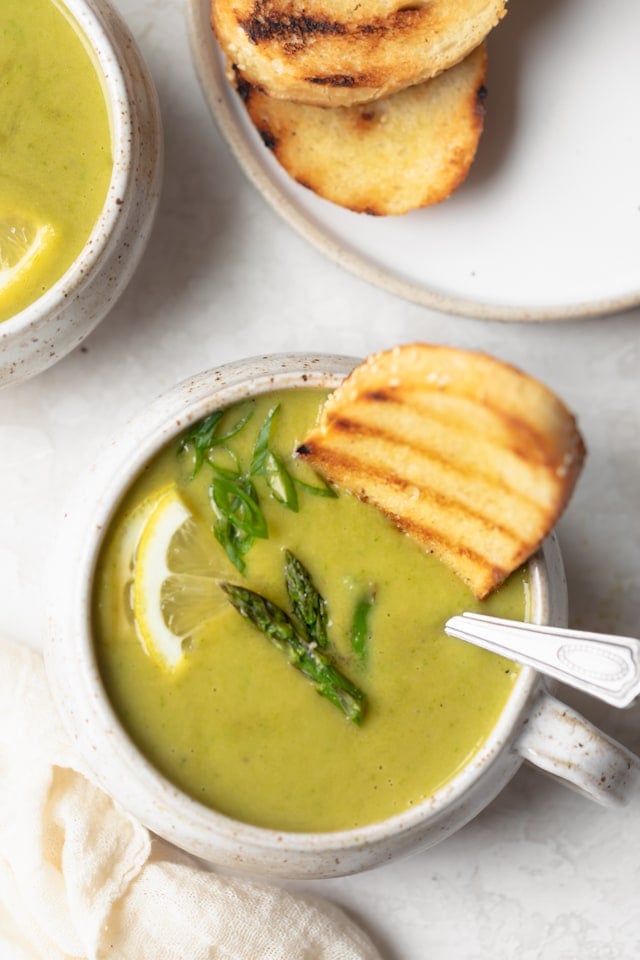 Grilled bread dipped into soup in mug bowl