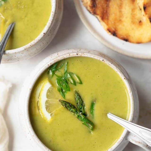 Close up of cream of asparagus soup in bowl with spoon