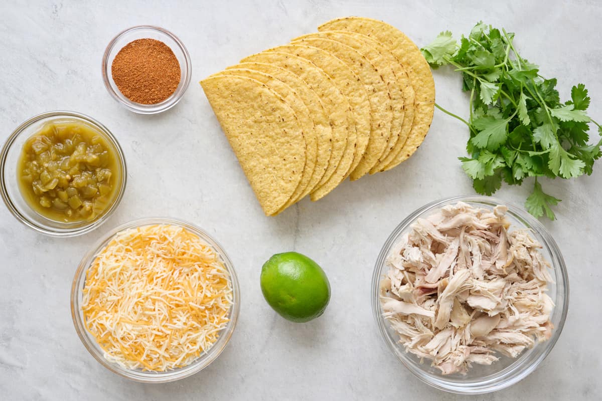Ingredients for recipe: green chilis, taco seasoning, shredded cheese, shredded chicken, lime, taco shells, cilantro.