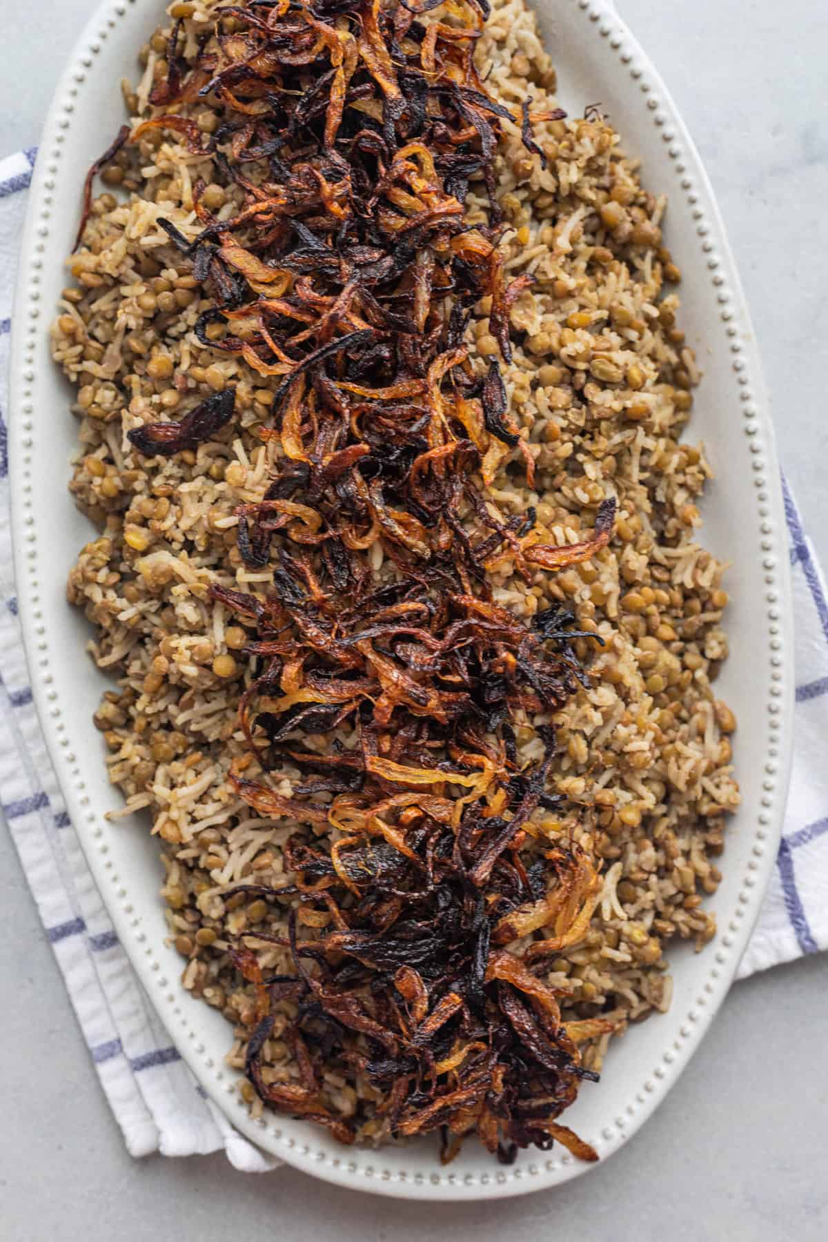 Mujadara topped with crispy onions on a large platter.