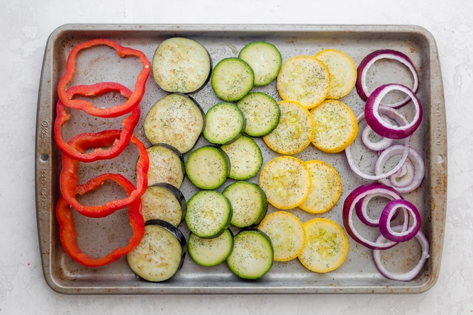 Sliced vegetables on a baking dish before roasting