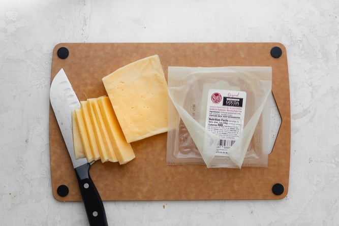 Slicing Gouda cheese on a cutting board