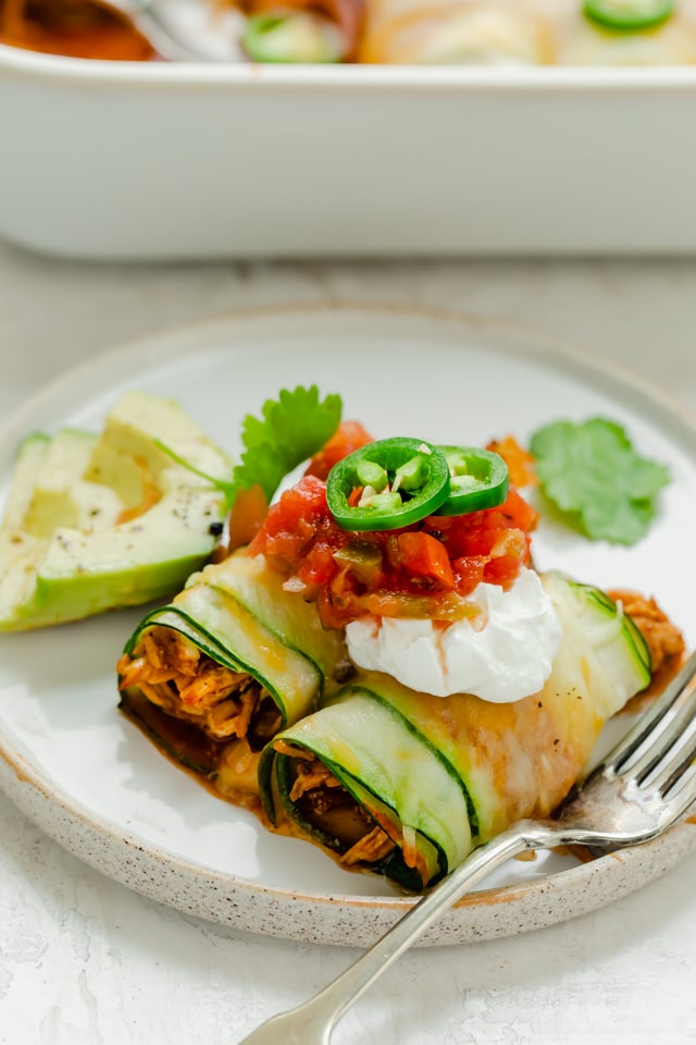 Two enchilada rolls on a plate with toppings