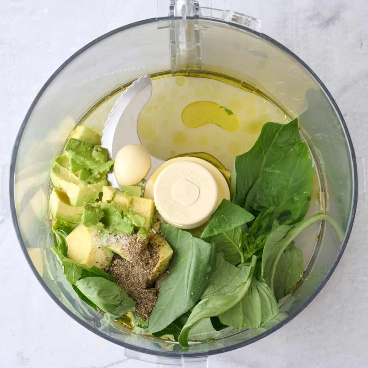 Avocado, basil, oil, lemon, garlic, salt and pepper in a food processor before blending.