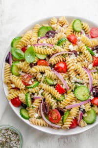 Final Greek Pasta Salad recipe in a large bowl with cucumbers, tomatoes, onions, olives and feta cheese