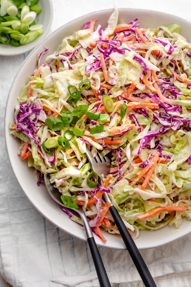 Serving some healthy coleslaw using large serving spoon and fork