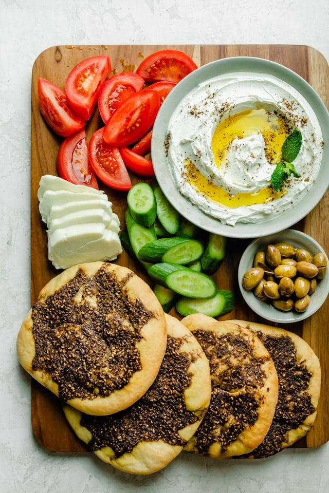 Baord mit Zaatar Manakeesh, Labneh, Oliven und Gemüse servieren