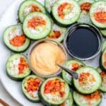 Large plate showing the cucumber rolls sliced into large bite-size pieces and served with soy sauce and spicy mayo