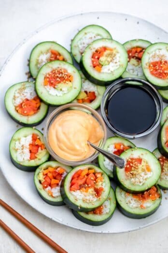 Large plate showing the cucumber rolls sliced into large bite-size pieces and served with soy sauce and spicy mayo
