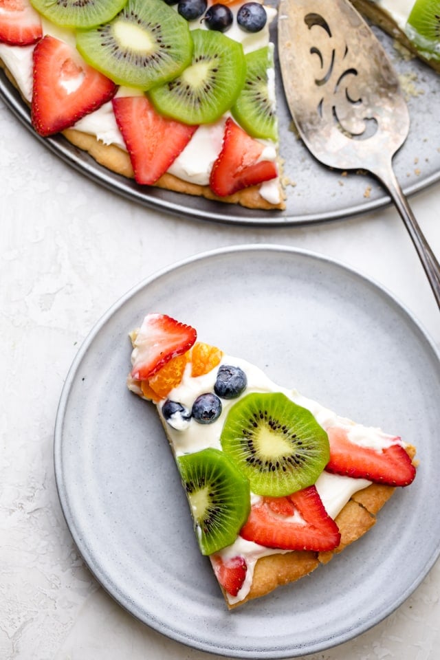 One slice of the fruit pizza removed on plated on a dessert plate