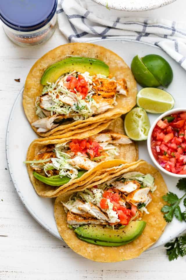 Large plate of grilled fish tacos topped with coleslaw, avocado and pico de gallo