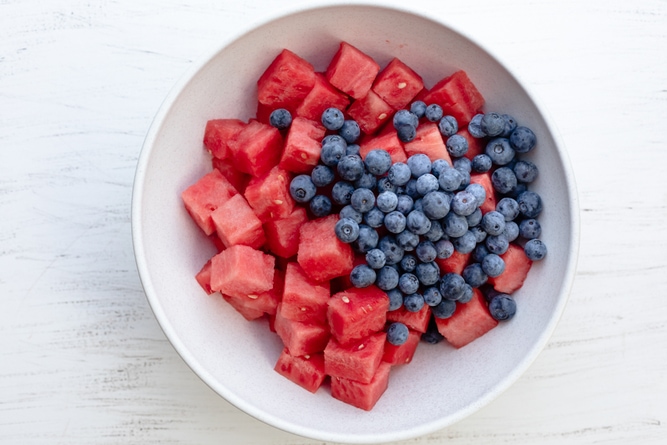 Large white bowl of cubed watermelon pieces with blueberries on top