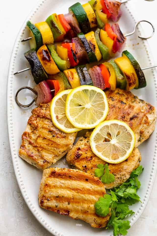 Cilantro chicken grilled with grilled veggie skewers on a white plate