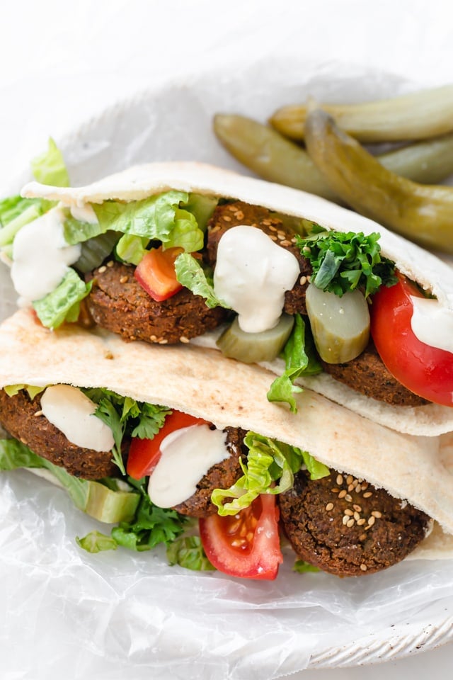 Falafel sandwich made with pickles, tomatoes, parsley and tahini sauce