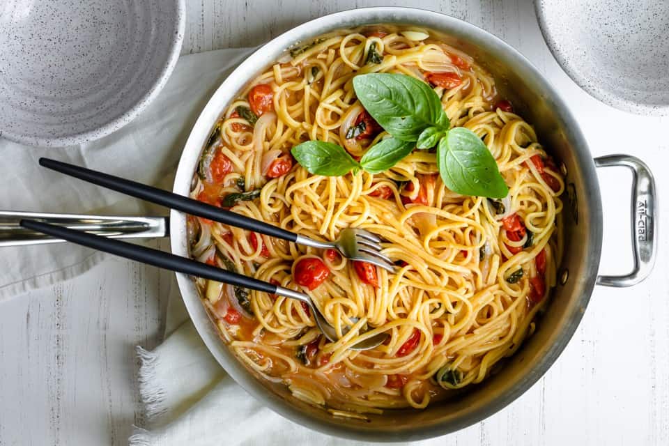 A pan of one pan pasta with serving utensils inside. 