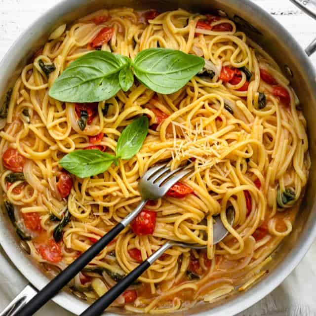 A pan of one pan pasta with serving utensils inside.