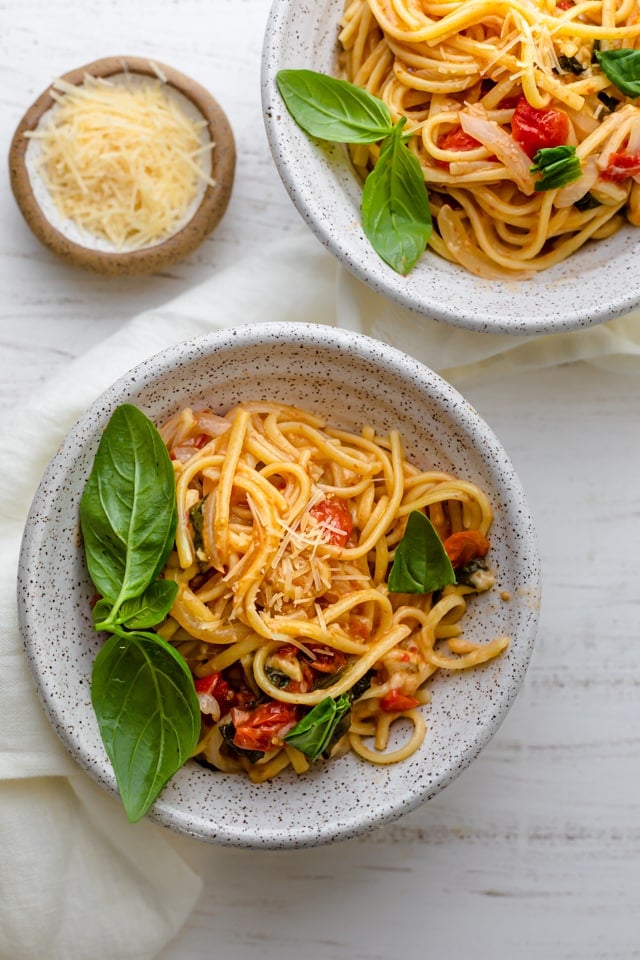 Vegetarian one pan pasta served in two large bowls with a side of parmesan cheese