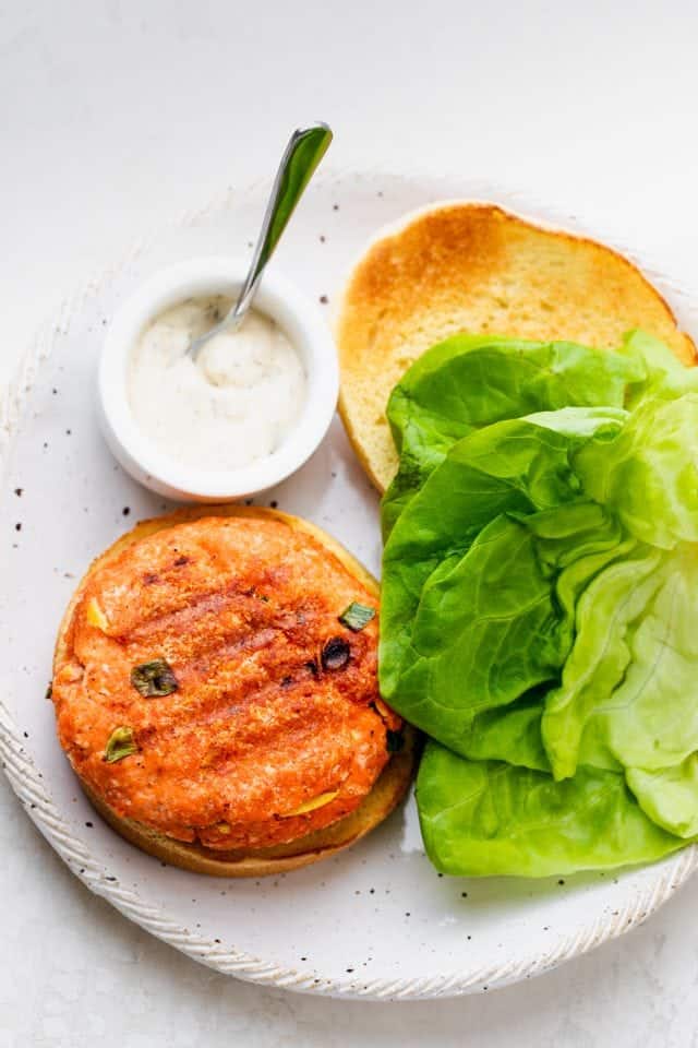 Salmon burgers made with a few ingredients and served with tartar sauce and lettuce
