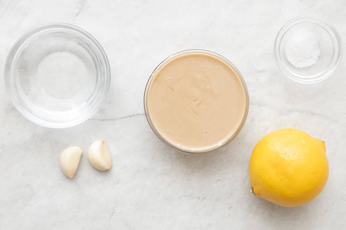 Ingredients for recipe before prepping: water, garlic, tahini, salt, and lemon.