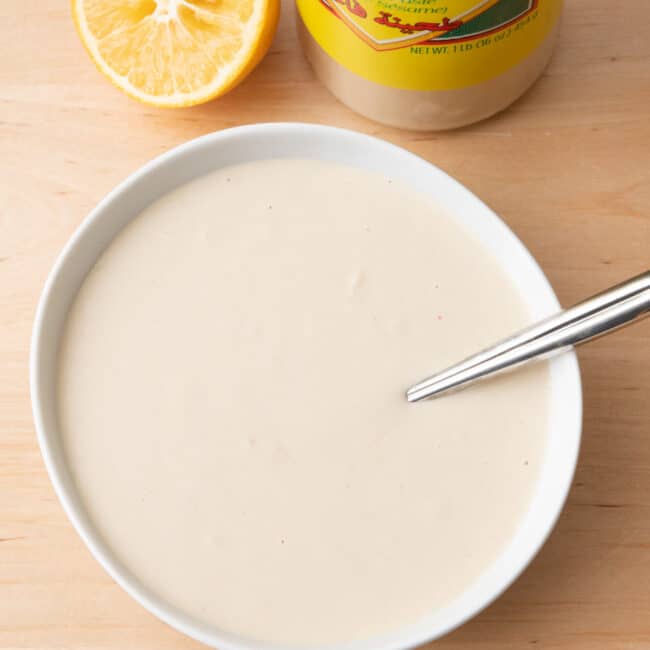 Tahini sauce in a large bowl with juiced lemons