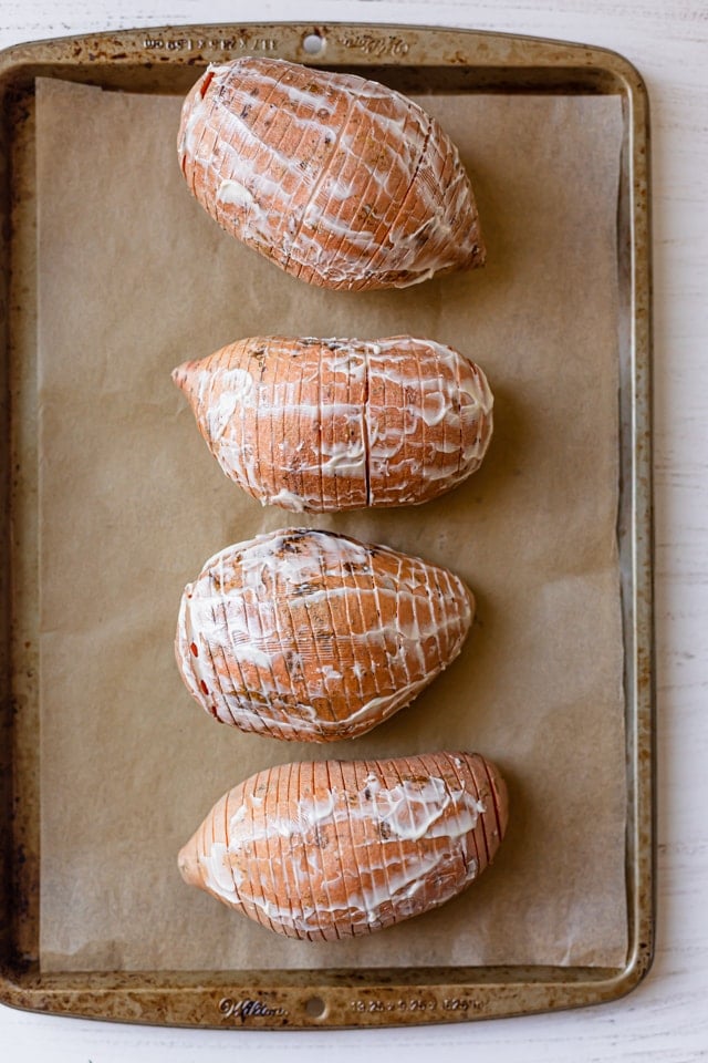 The potatoes rubbed with butter on a baking dish before baking