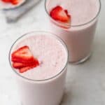 Two glasses of strawberry banana smoothie topped with strawberries