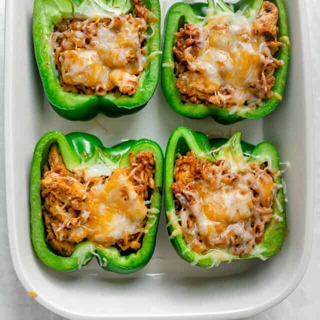 Chicken stuffed peppers in a white baking dish when they come out of oven