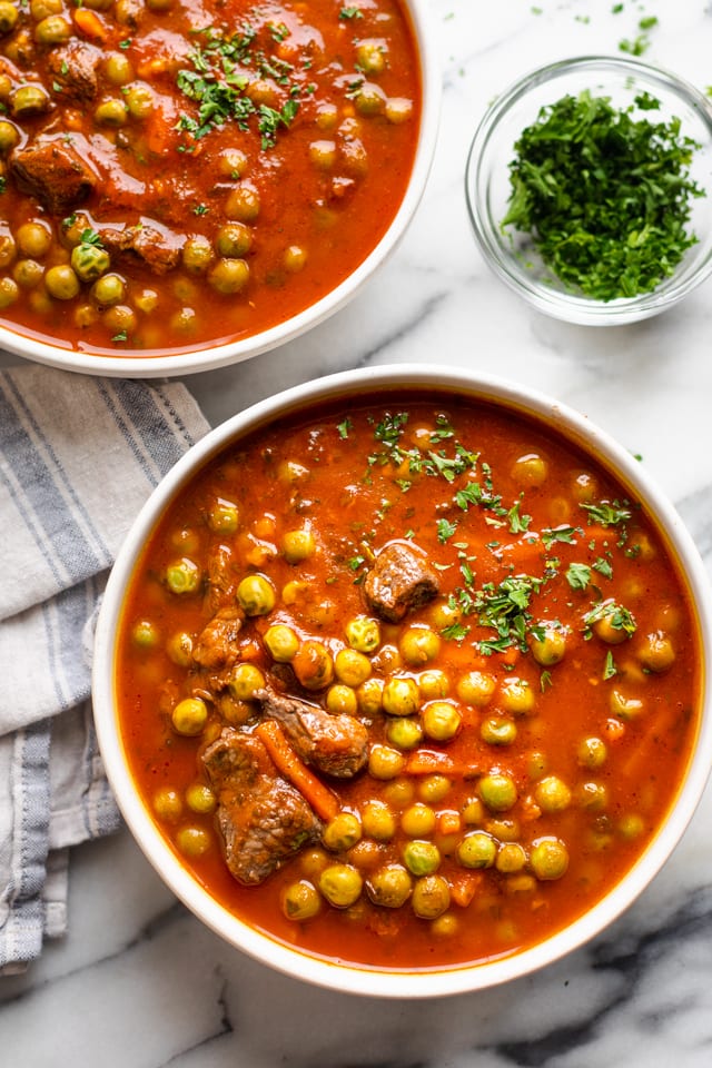 Two large bowls of the peas and carrots stew with side of parsley