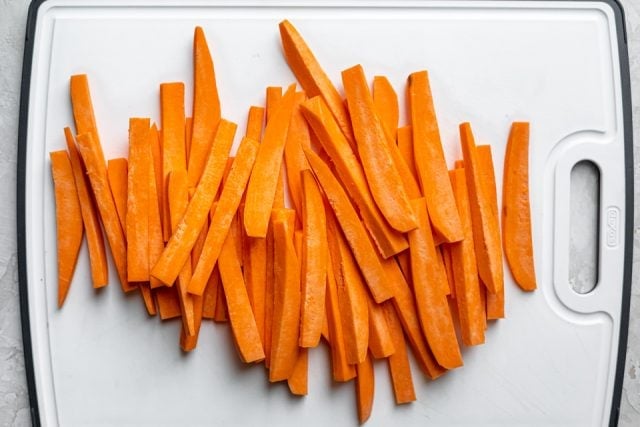 Sliced raw sweet potatoes on a cutting board