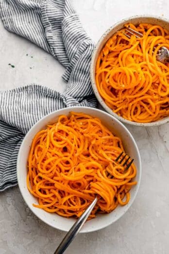 Two bowls of butternut squash noodles with forks inside bowls