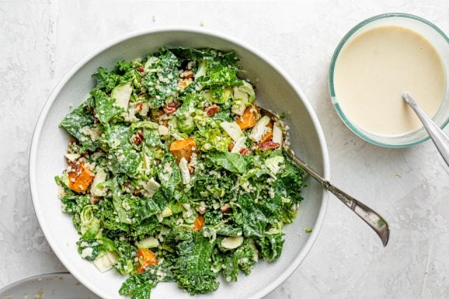 The tossed salad in a large bowl with a side of tahini dressing