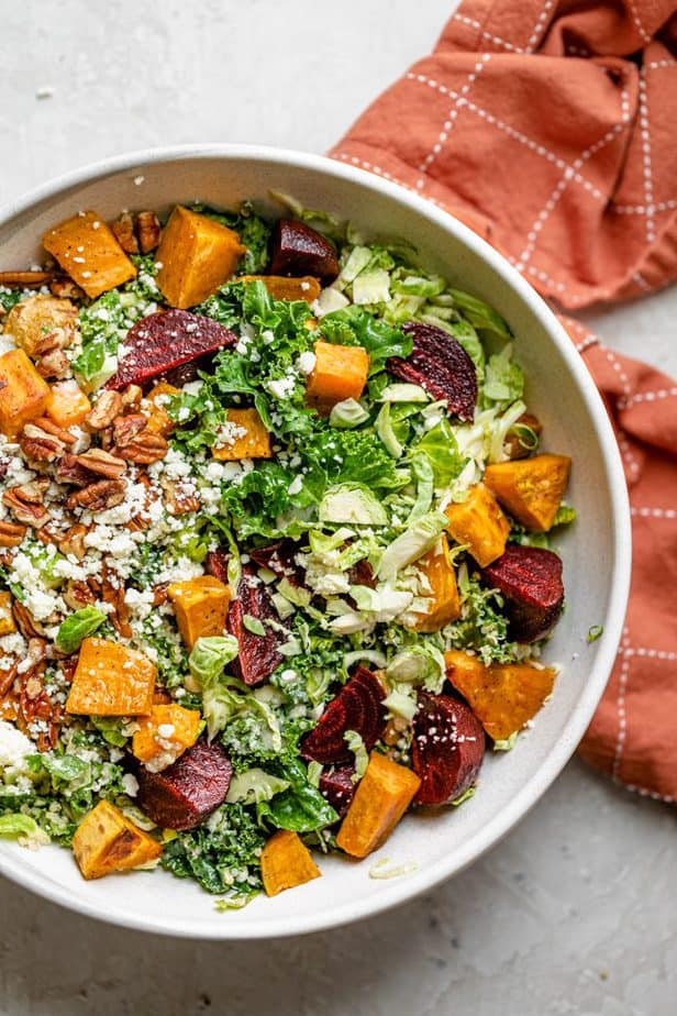 Fall harvest salad in a large bowl with an orange linen towel nearby