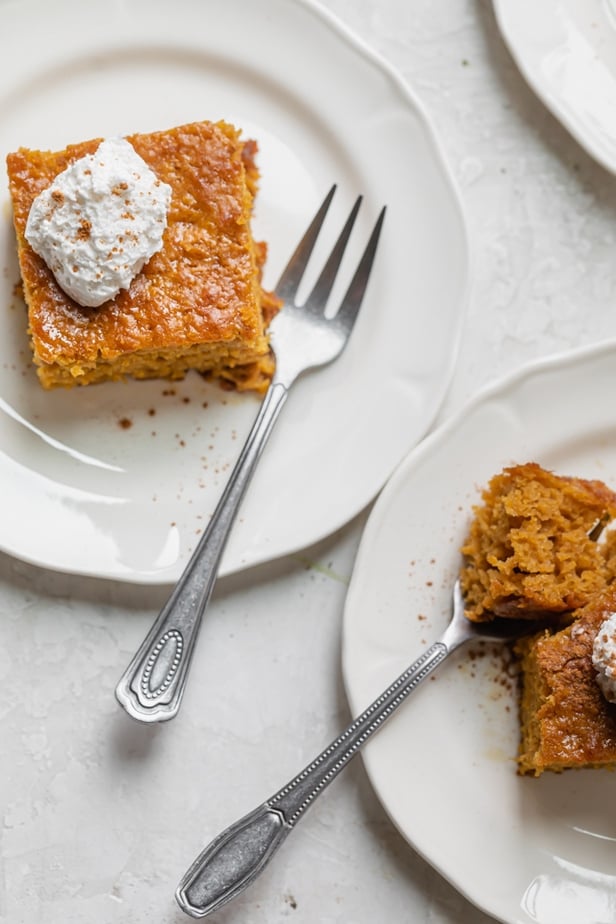 Two white plates with pieces of pumpkin bars on them and forks