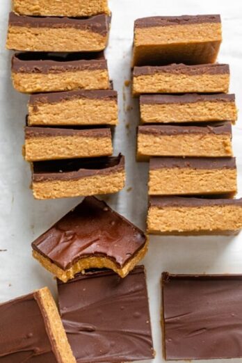 Stack of chocolate peanut butter bars with one bite taken out of one of them