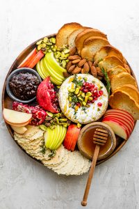 Baked Brie recipe on a cheese board with toast, crackers, fruit and accompaniments