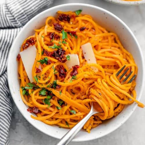 A bowl of butternut squash noodles with a fork resting inside.